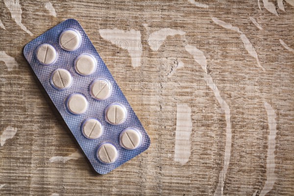 Pills in blister pack on vintage wooden board with organized copyspace medical concept