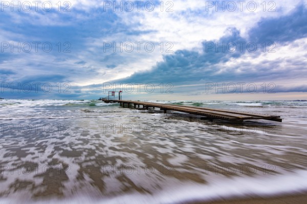 Sea landscape with beautiful clouds in blue tones, with a pier on the horizon