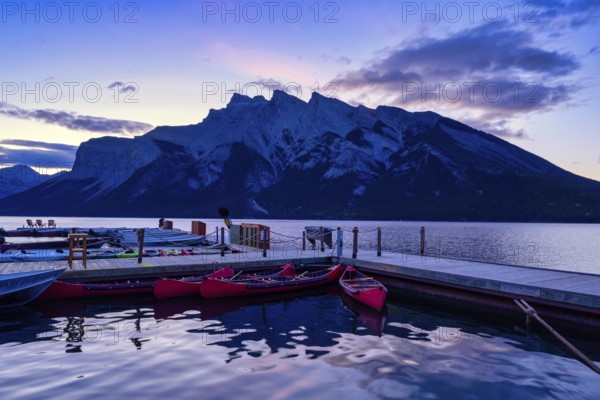 Beautiful autumn landscape scene in lake and mountain in background in west Canada, colour kayaks and canoes and small boats