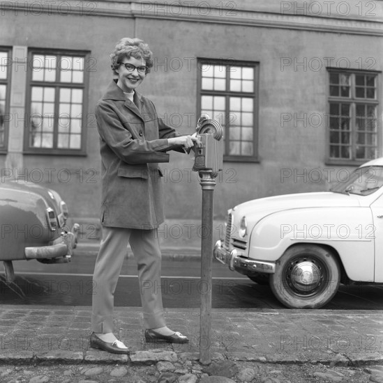 In the 1950s. A woman is pictured in the street and at a parking meter. A device used to pay for parking. When having put in a coin, you turned the lever and an arrow inside the meter showed for how long you had paid for parking. Sweden 1959 Kristoffersson ref CF59-5