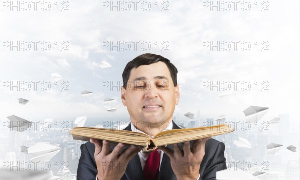 Happy businessman holding open old book. Smiling man in suit standing on downtown background with flying paper planes. Lawyer holding big legal regulation book. Business accounting and consulting