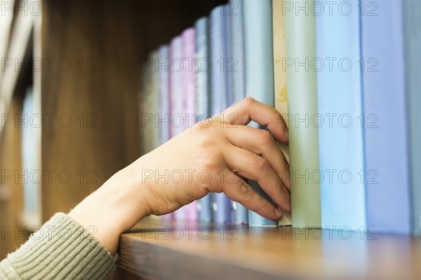 Hand pulling a book off the shelf. Blue colors books