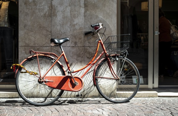 Red bike with basket on italian street. Typical italian architecture on background. Sunny day. Typical italian style