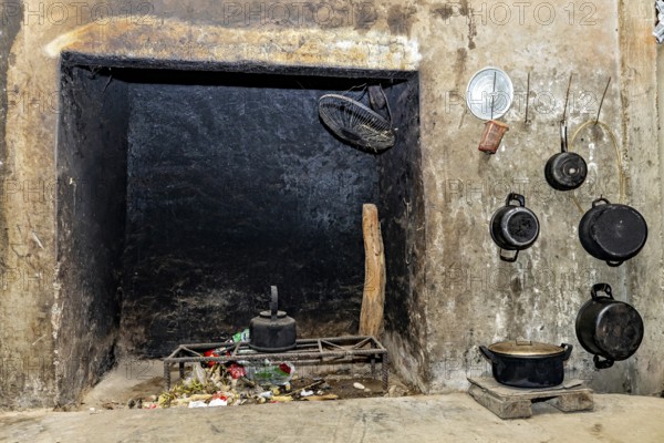 Old fireplace with hanging pots and pans, rustic ambience with traces of soot and a scale on the wall, The interior of a farmhouse in the Sa Pa area of Vietnam