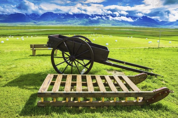 Old wooden sledge and two-wheeled cart on the lawn. The reconstituted village - Museum Vikings in Iceland
