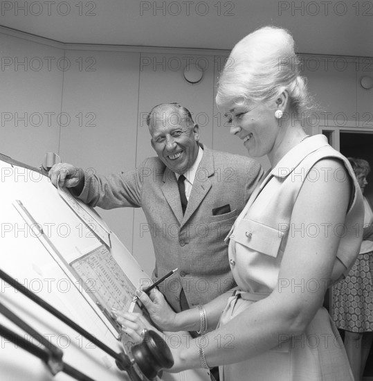 Chocolate in the 1960s. A woman in an office has her hair in the typical Beehive hairstyle, in which long hair is piled up on the top of the head and giving some resemblance to the shape of a traditional beehive. Sweden 1965 Conard ref 5264