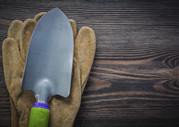 Metal trowel protective gloves on wooden board gardening concept