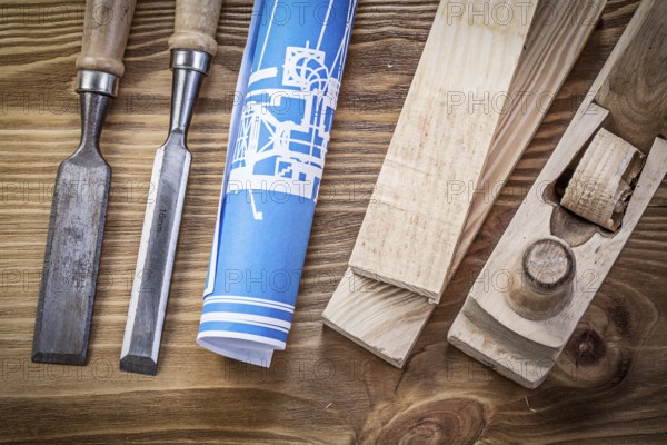 Blue rolled construction drawing shaving plane chisels wooden studs on wood board