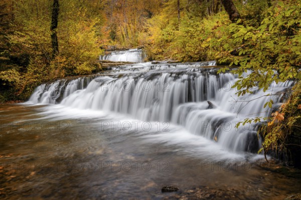 A beautiful autumn forest landscape with idyllic waterfall and pool