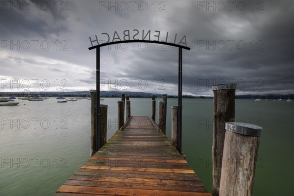 Wooden footbridge leads into a lake under a stormy sky, Allensbach, Untersee, Lake Constance, Constance District, Baden-Württemberg, Germany, Europe