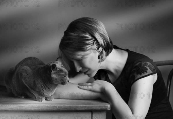 Portrait of a woman with her Russian Blue pedigree cat showing her affection