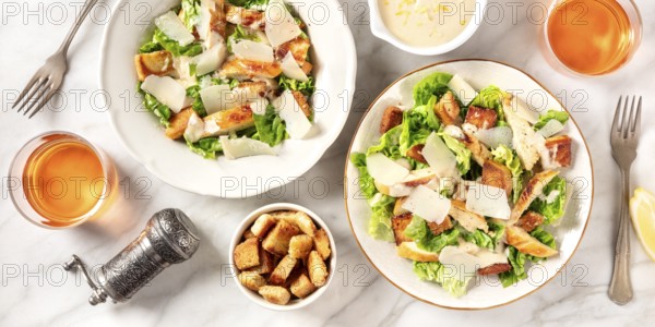 Caesar salad panorama with the classic sauce and wine, shot from above on a white marble background