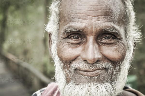 Sunderban, Bangladesh, circa July 2012: Old native man with white beard and hair wears colourful scarf and brown shirt and holds wooden stick in hand in Sunderban, Bangladesh. Documentary editorial, Asia