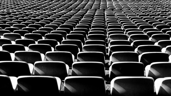 A black and white view of endless rows of empty chairs in a stadium