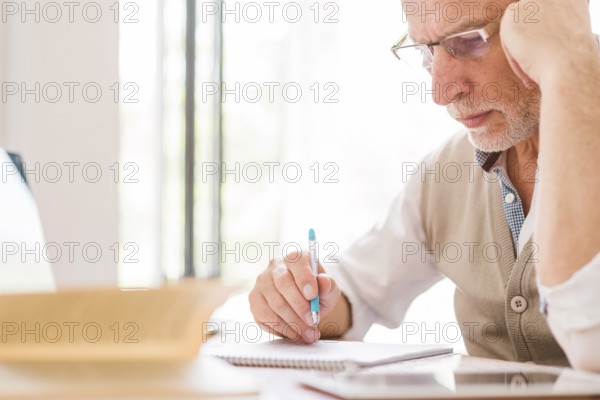 Senior professor glasses writing notebook classroom