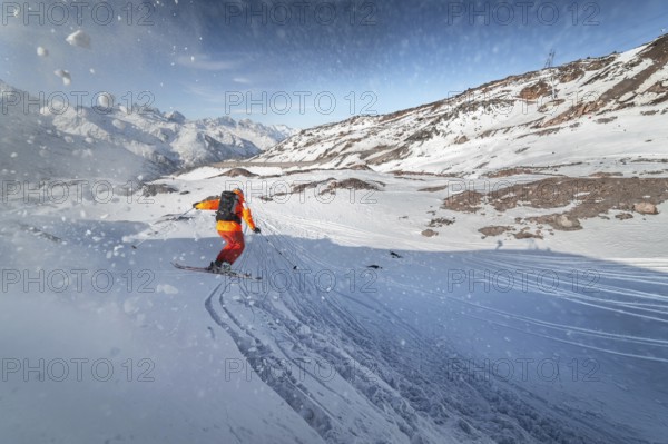 Skier rides on a snowy slope on a sunny day at sunset against the backdrop of the mountains. The concept of winter skiing