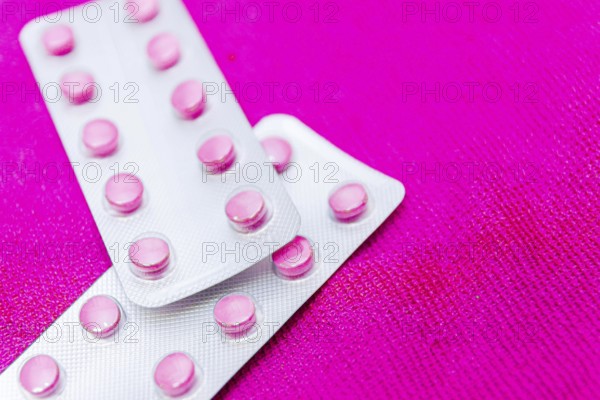 Pink pills in a blister on a pink background