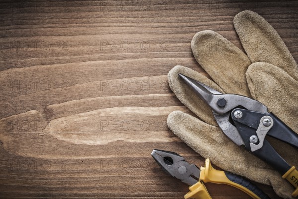 Steel cutter pliers leather safety gloves on wooden board