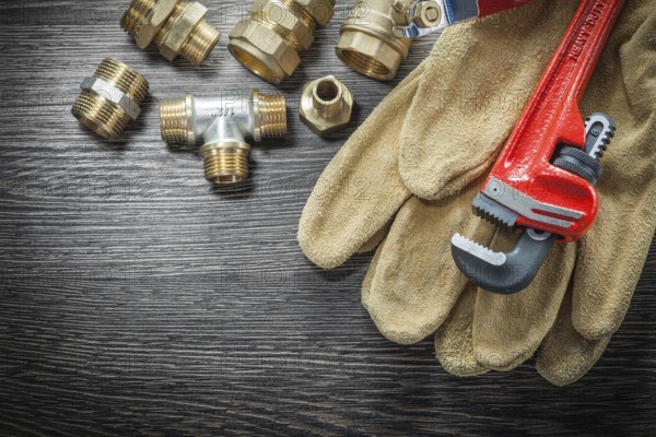 Plumbing monkey wrench pipe fittings protective gloves water valve on wooden board