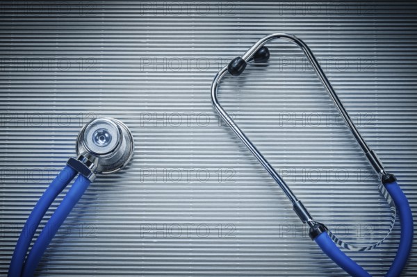 Medical auscultator on striped background