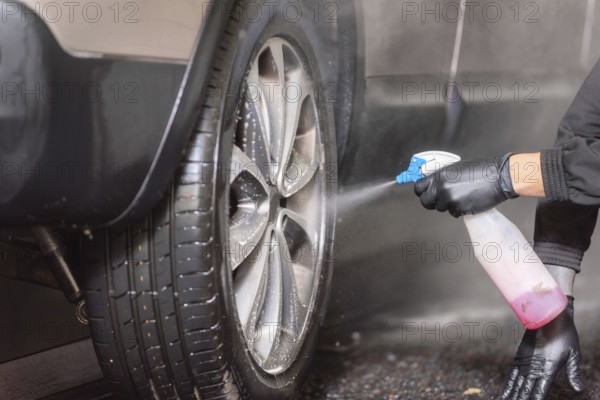 Professional car washer cleaning car alloy wheels
