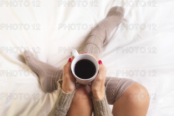 Woman sitting in bed drinking a cup of coffee
