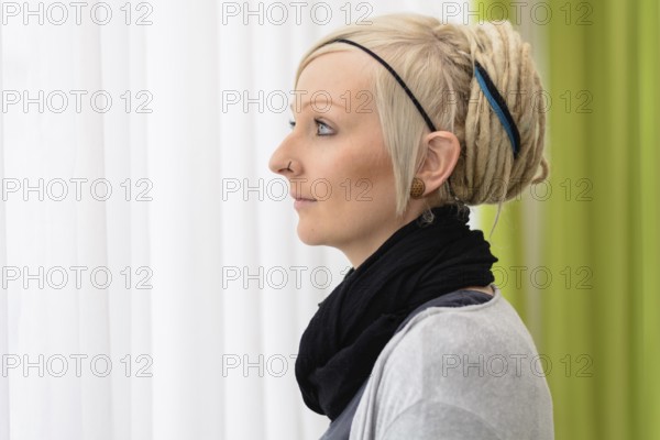 Young woman looks thoughtfully out of the window - portrait with text space