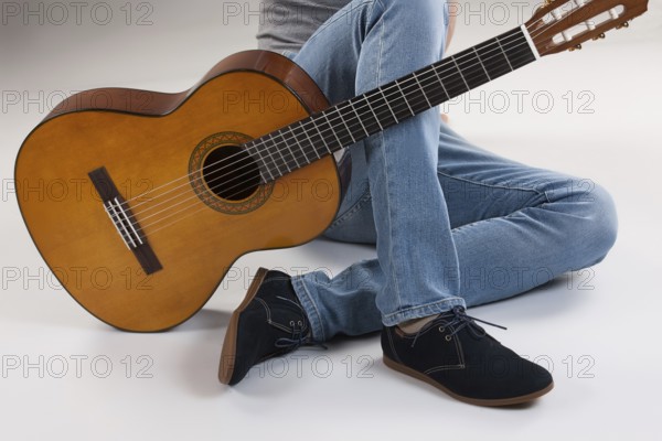 Man's legs and guitar on a studio background