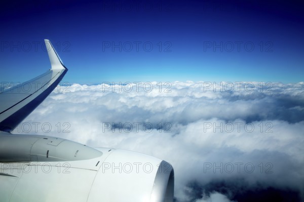 Airplane wing flying over fluffy clouds in blue sky high view