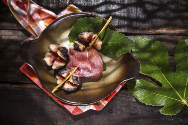 Presentation on plate skewer with figs and ham