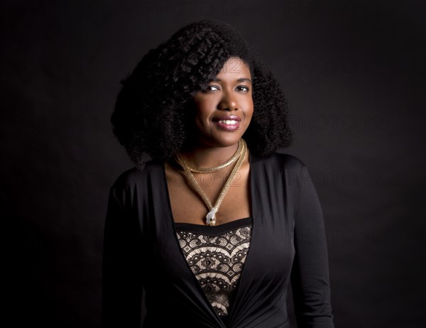 Beautiful young black woman is wearing dark dress on grey background, Toronto, Canada, North America