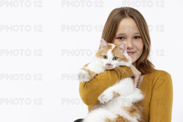 A cheerful girl lovingly holds her fluffy cat, radiating joy and warmth while wearing a cozy sweater