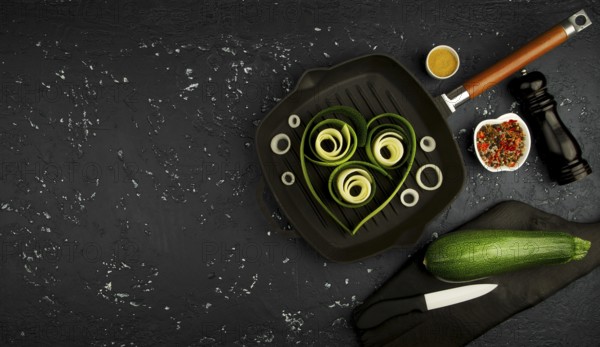 Fresh green zucchini in a pan on a dark table. The view from the top. Copy space