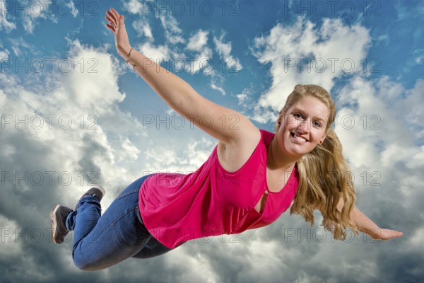Young girl flies laughing high in clouds against a blue sky