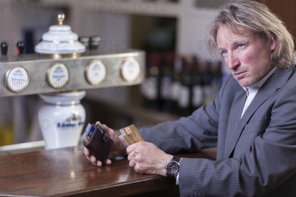 Man in suit paying at a counter with a credit card, Mindelheim, Bavaria, Germany, Europe