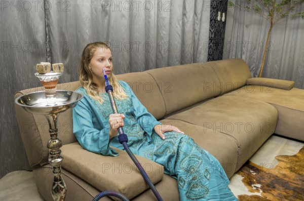 Woman smoking traditional Hookah (Narguile, Shisha, Chicha, Arguile), equipment used for smoking tobacco, widely, very widespread throughout the Middle East