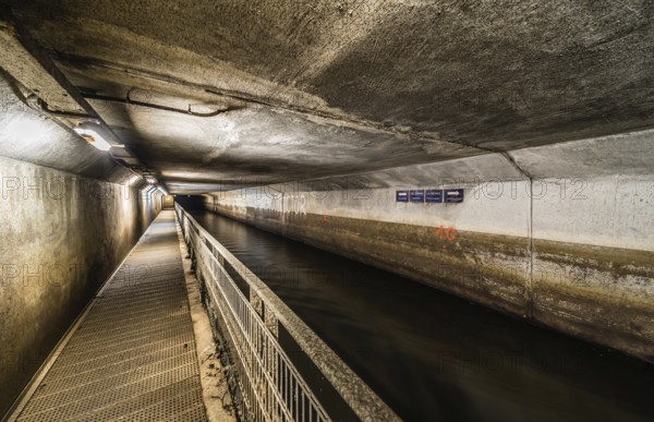 Anderlecht, Brussels, Belgium, 07 16 2019- The covered river La Senne, with a metal walking path at the sewer museum and a man walking, Europe