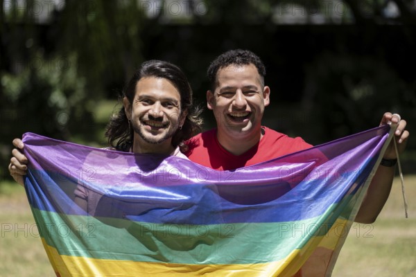 Couple of gay latin men holding the LGBT flag