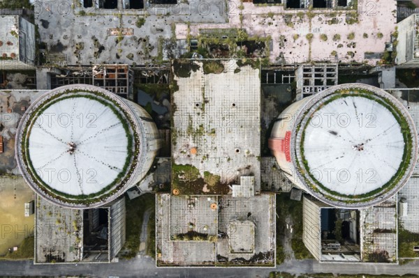 Aerial view from drone of abandoned and ruined Nuclear Power Plant or station, round tower of atomic reactor, large industrial demolished building.