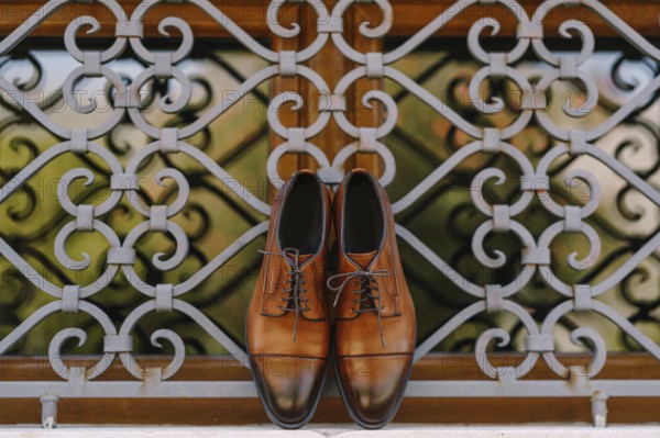 Stylish brown men's shoes made of genuine leather by the window with a metal lattice.