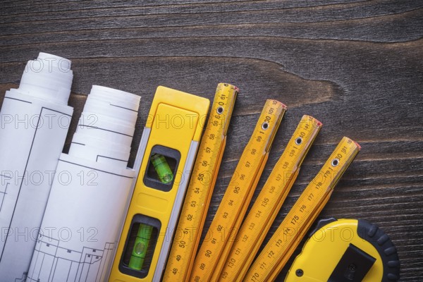 Close up view of blueprint rolls construction level tape-line and wooden meter on vintage wood board maintenance concept