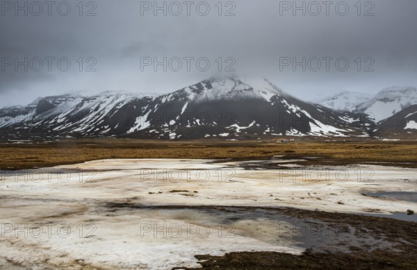 Icelandic landscape with frozen lake, mountains and meadow land covered in snow at snaefellsnes peninsula in Iceland