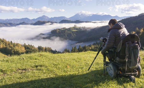 Man on wheelchair taking photos of beautiful landscape