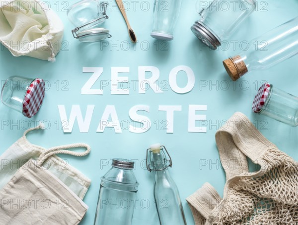 Zero waste concept. Textile eco bags, glass jars and bamboo toothbrush on blue background with Zero Waste white paper text in center. Eco friendly and reuse concept. Top view or flat lay