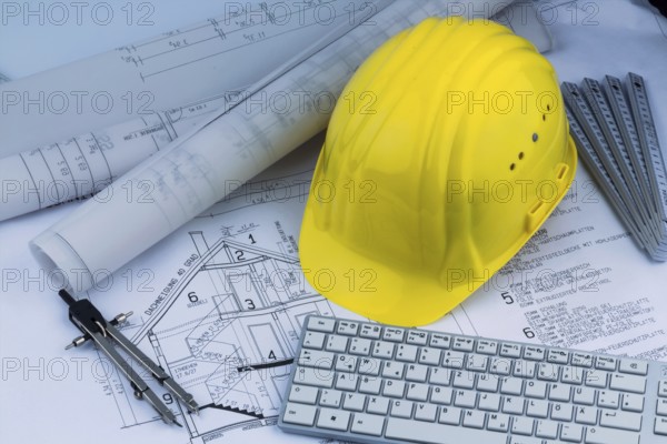 An architect's construction plan with a builder's helmet. Symbolic photo for financing and planning a new house