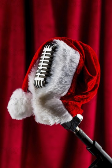 An old retro microphone with a Christmas hat in front of a red velvet background. Austria