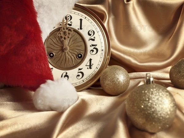 New year theme with balls, vintage clock and Santa hat over golden drapery
