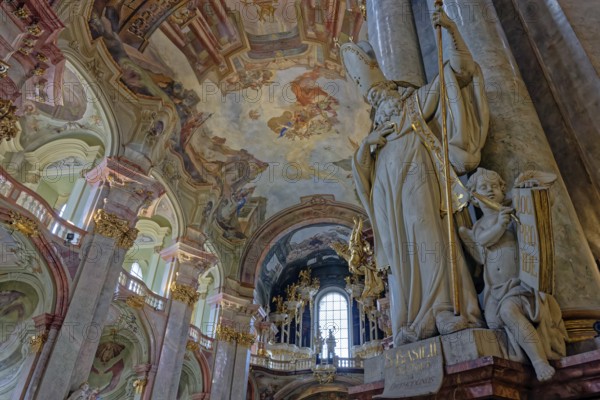 Majestic baroque St. Nicholas Church interior with a large statue and intricate frescoes under arches, Prague, Czech Republic, Europe