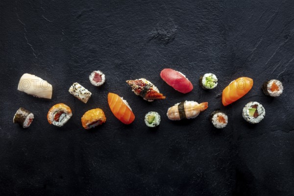 Sushi overhead flat lay shot. Rolls, maki, nigiri on a black slate background, Japanese food. Salmon, eel, shrimp, tuna etc with rice, with copy space, Food photography, Food photography