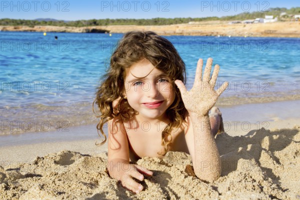 Little girl greeting hand gesture in sandy beach of Ibiza Cala Conta